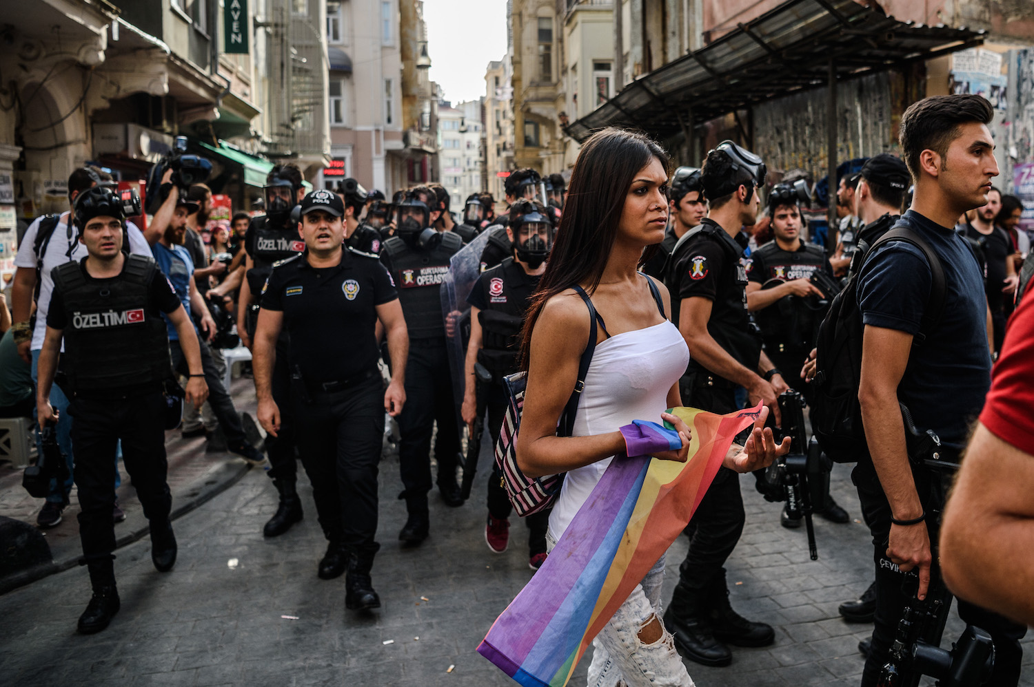 A woman holds a rainbow flag as Turkish anti-riot police officers disperse demonstrators gathered for a rally staged by the LGBT community on Istiklal avenue in Istanbul on June 19, 2016. Turkish riot police fired rubber bullets and tear gas to break up a rally staged by the LGBT community in Istanbul on June 19 in defiance of a ban. Several hundred police surrounded the main Taksim Square -- where all demonstrations have been banned since 2013 -- to prevent the "Trans Pride" event taking place during Ramadan.  / AFP / OZAN KOSE        (Photo credit should read OZAN KOSE/AFP/Getty Images)
